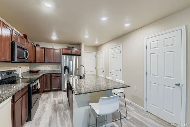 a kitchen with granite countertop a table chairs microwave and cabinets