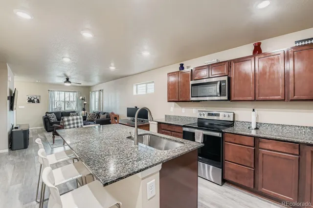 a kitchen with stainless steel appliances granite countertop a sink a stove counter space and cabinets