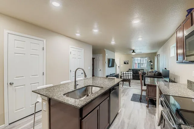 a kitchen with granite countertop a stove a sink a dining table and chairs with wooden floor