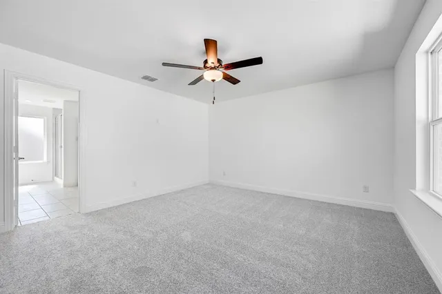 an empty room with windows and fan