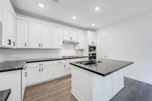 a kitchen with stainless steel appliances granite countertop a sink stove and cabinets