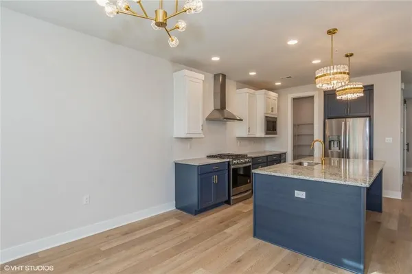 a large kitchen with granite countertop a large counter top a sink stainless steel appliances and cabinets