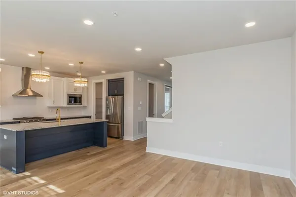 a large kitchen with stainless steel appliances a large counter top a refrigerator and a sink