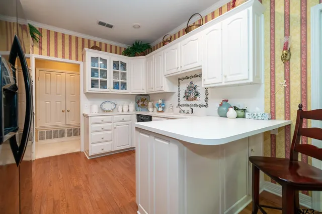 a kitchen with white cabinets and wooden floor