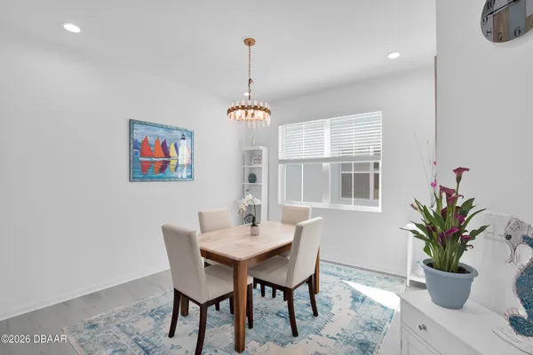 a dining room with wooden floor a chandelier a wooden table and chairs