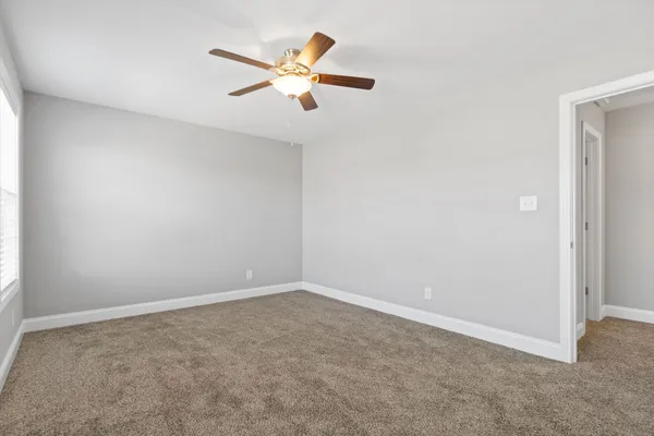 an empty room with a chandelier fan and a window