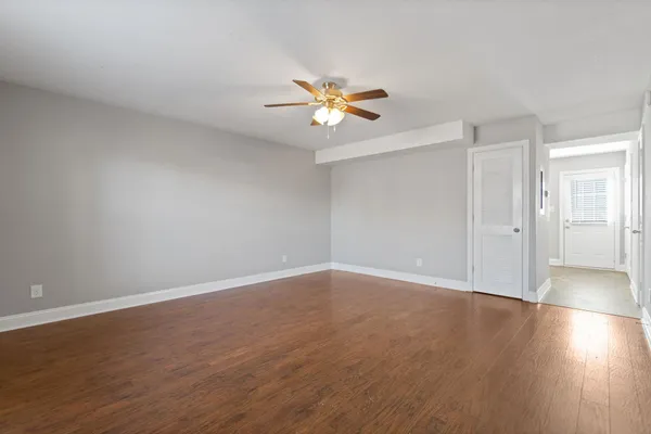 a view of a room with wooden floor and a ceiling fan
