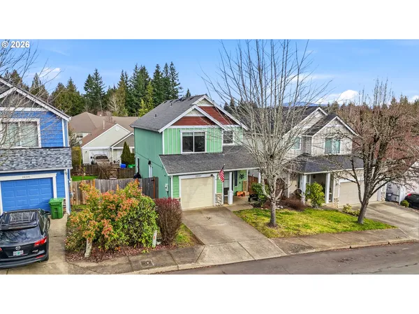 a view of a white house with a large tree and a yard in front of it