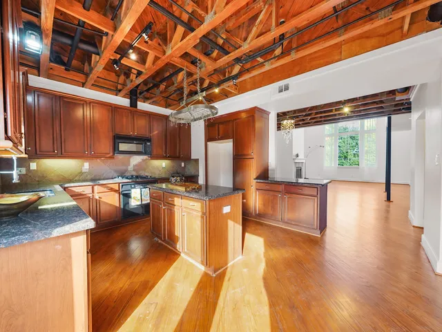 a kitchen with stainless steel appliances granite countertop a stove a sink and a wooden floors