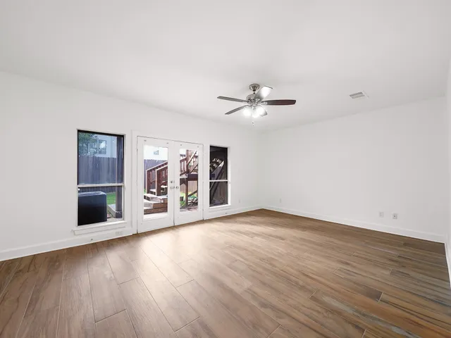 a view of an empty room with wooden floor and a window