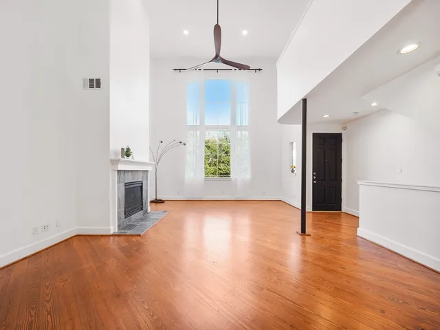 an empty room with wooden floor staircase and windows