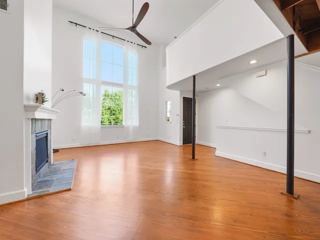 a view of an empty room with window and wooden floor