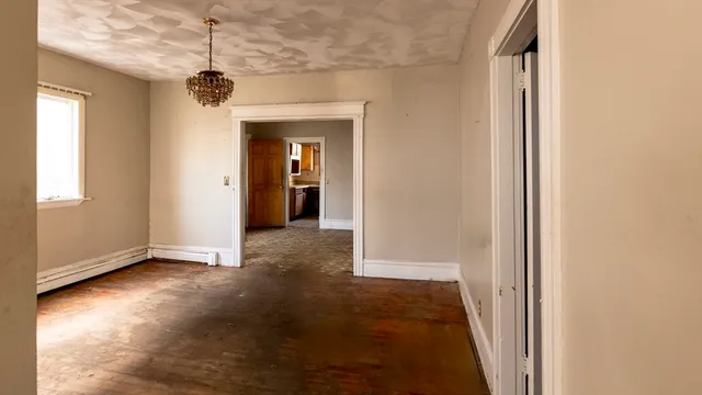 a view of a room with a chandelier and wooden floor