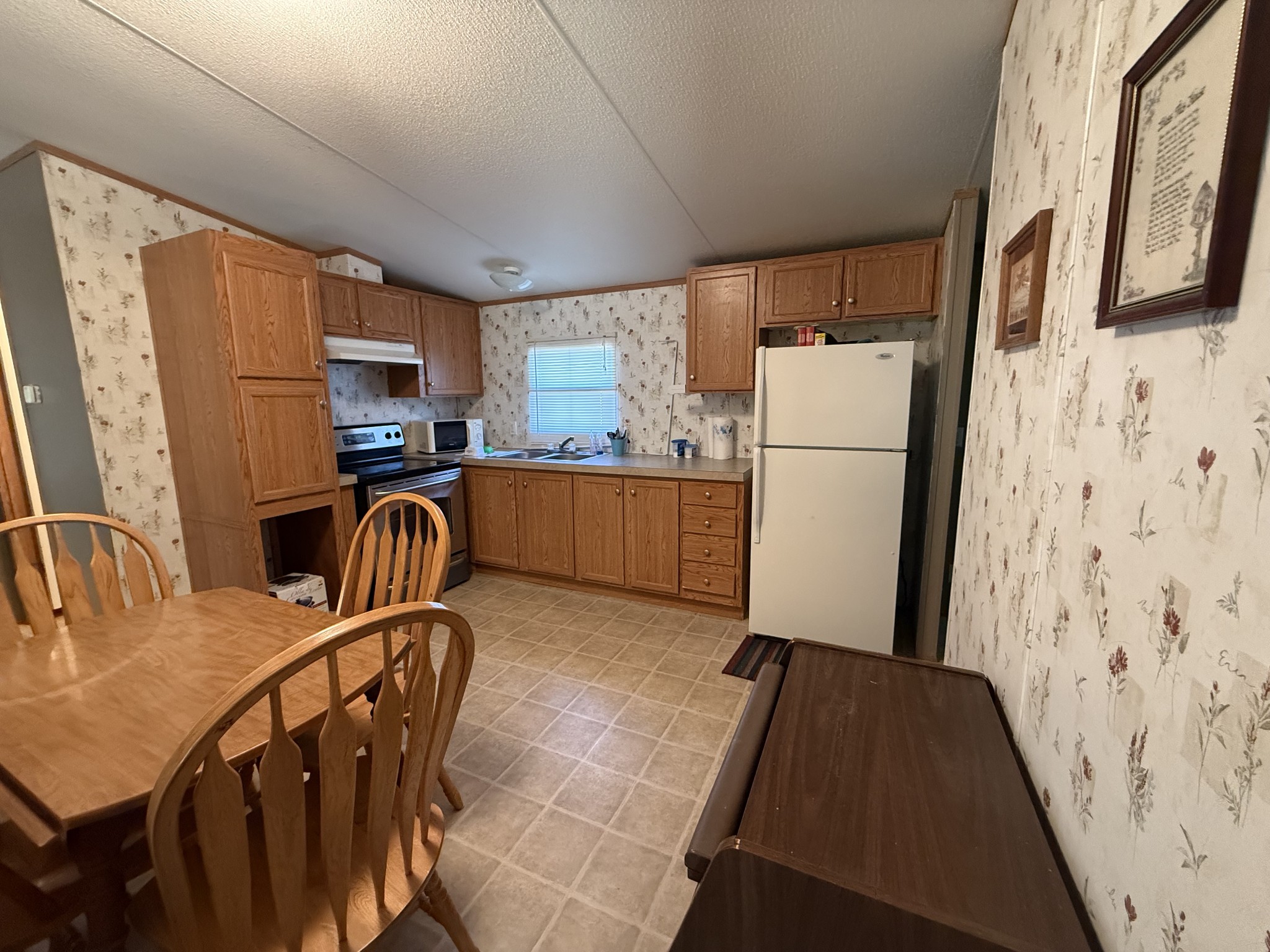 213 Alps Drive Hohenwald, TN 38462 - Photo 5 of 17 a kitchen with stainless steel appliances a refrigerator a sink a stove a microwave a dining table and chairs with wooden floor