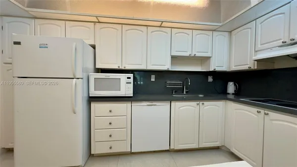 a kitchen with white cabinets and white appliances