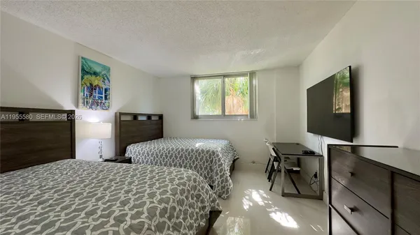 a bedroom with double bed and a flat tv screen on dresser