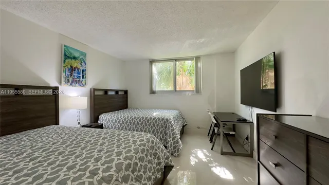 a bedroom with double bed and a flat tv screen on dresser