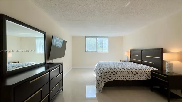 a bedroom with a bed and a flat tv screen on a dresser