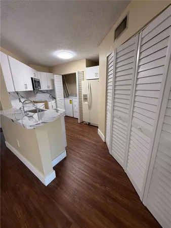 a living room with stainless steel appliances kitchen island hardwood floor and a window