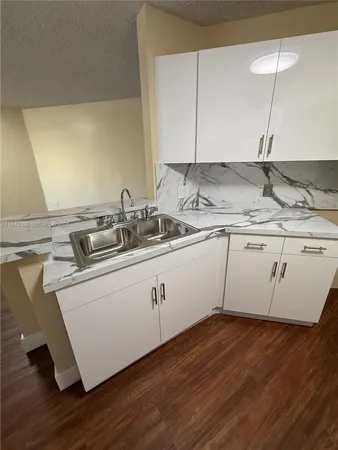 a kitchen with a sink cabinets and wooden floor