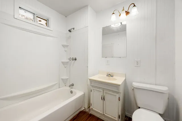 an empty room with wooden floor chandelier and windows