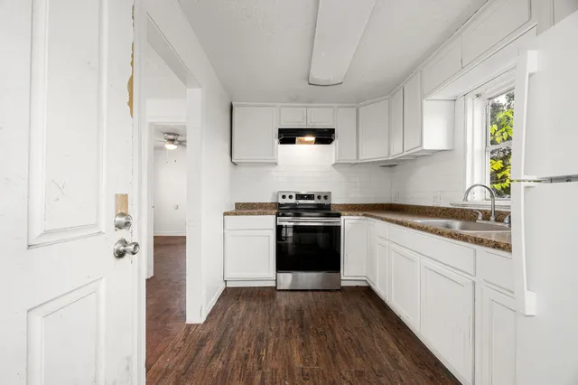 a kitchen with granite countertop stainless steel appliances white cabinets granite counter tops and a wooden floors