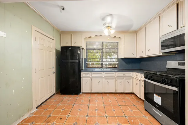 an empty room with wooden floor ceiling fan and windows