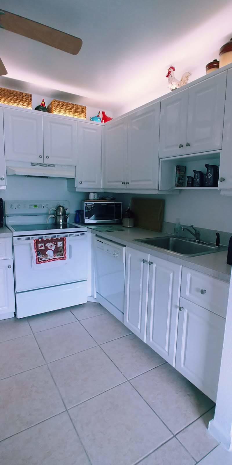95 Monaco Boulevard, Unit B Delray Beach, FL 33446 - Photo 29 of 46 a kitchen with stainless steel appliances a sink a stove and cabinets
