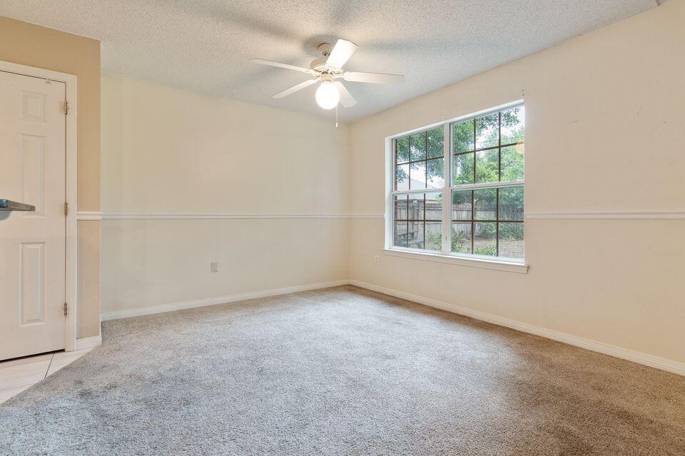 209 Warrior Street Crestview, FL 32536 - Photo 12 of 18 an empty room with windows and chandelier fan