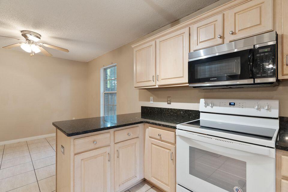 209 Warrior Street Crestview, FL 32536 - Photo 9 of 18 a kitchen with granite countertop white cabinets and white appliances