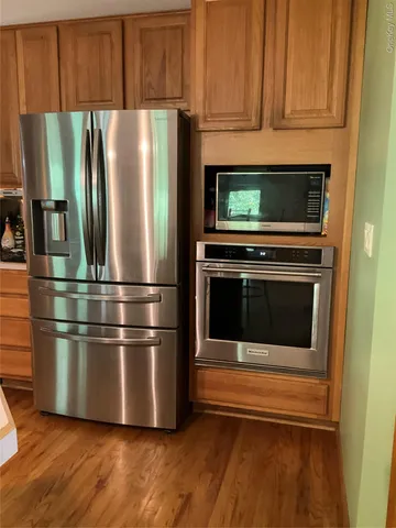 a kitchen with stainless steel appliances wooden cabinets and a wooden floor
