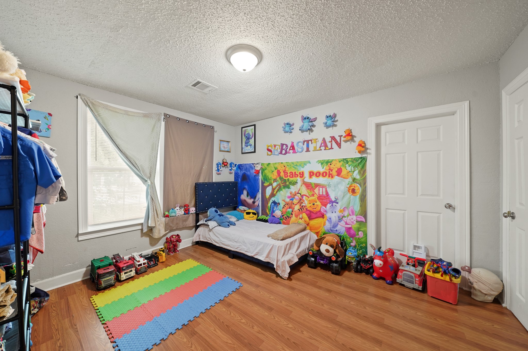 5307 Crane Street Houston, TX 77026 - Photo 27 of 41 4001 Lockwood Dr. Spacious bedroom featuring stylish wood-look flooring, a large window for natural light, and plenty of space for furniture or play.