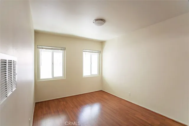 a view of an empty room with wooden floor and closet