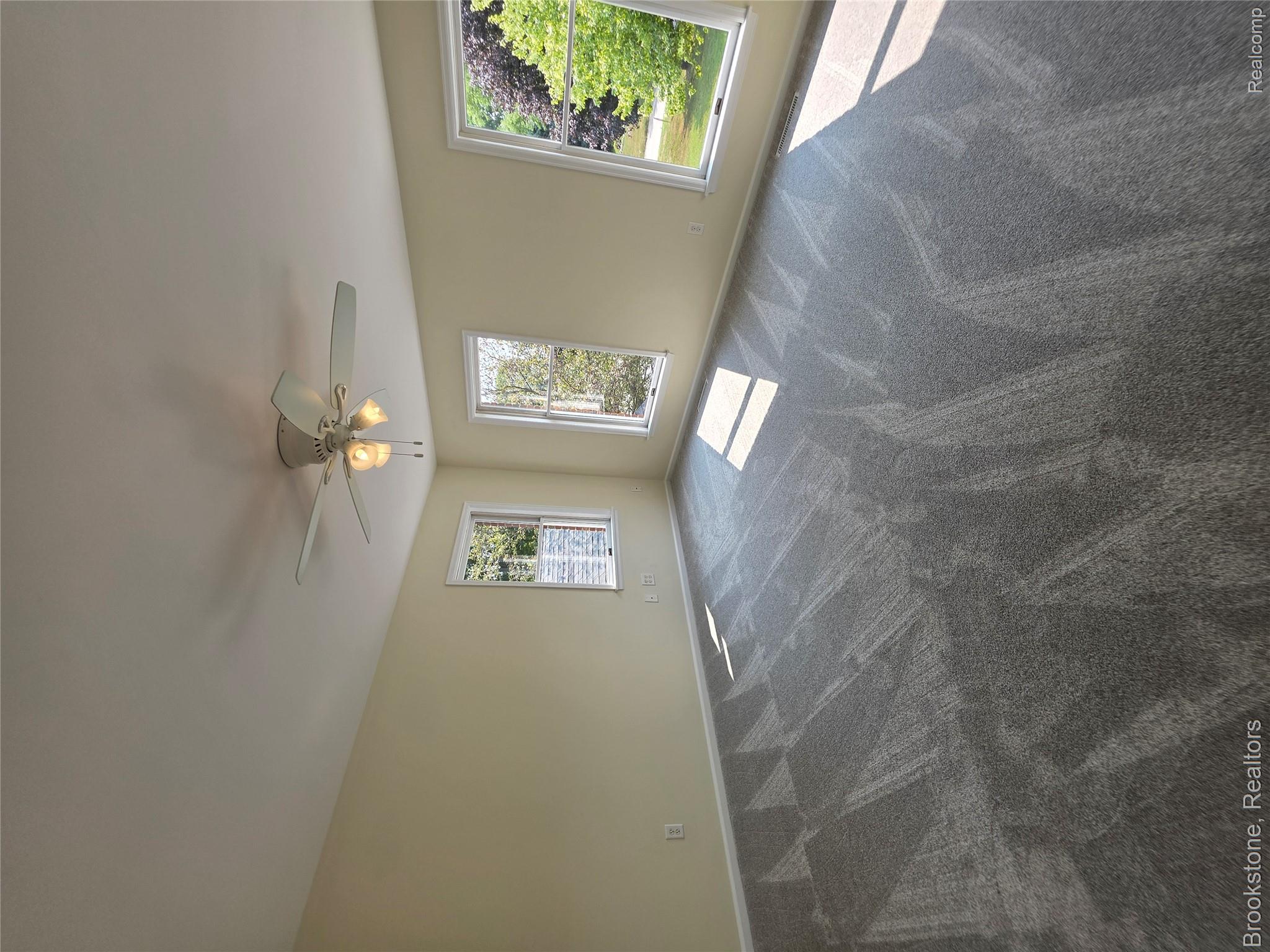1210 Springborrow Drive Flint, MI 48532 - Photo 33 of 34 Spacious room with light-toned walls, multiple windows, and patterned carpet flooring