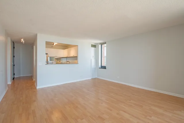 a view of an empty room with wooden floor and a window