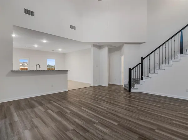 a view of an empty room with wooden floor and stairs