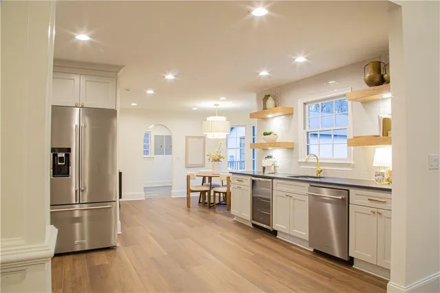 a kitchen with stainless steel appliances granite countertop a refrigerator a sink dishwasher a stove and white countertops with wooden floor