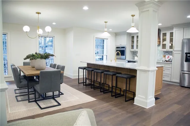 a kitchen with stainless steel appliances kitchen island granite countertop a table chairs refrigerator and sink