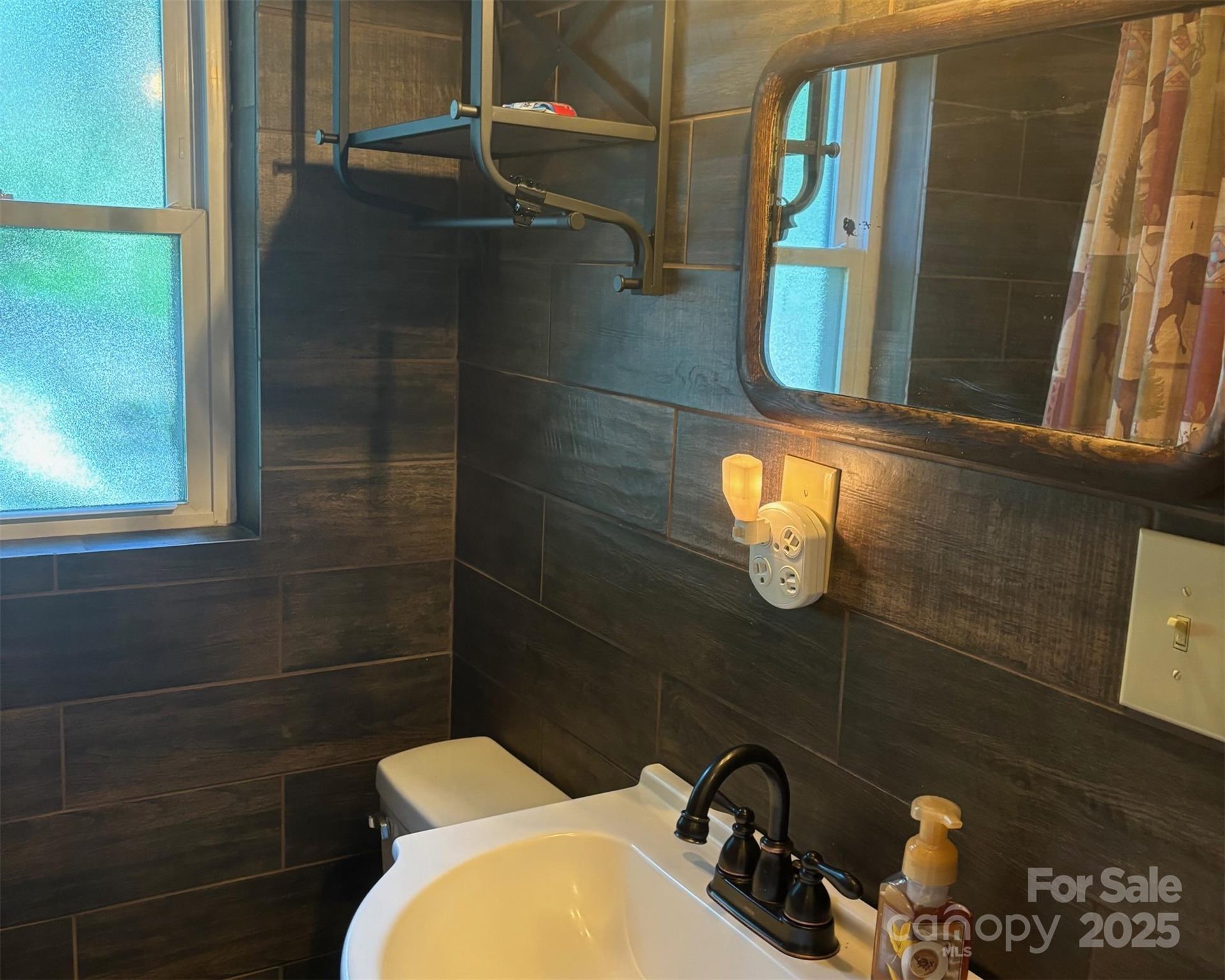 1555 Soco Road, Unit 12 Maggie Valley, NC 28751 - Photo 7 of 12 a bathroom with a toilet a sink and mirror