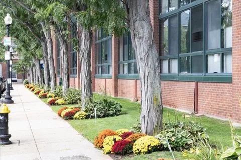a front view of a building with trees and green space