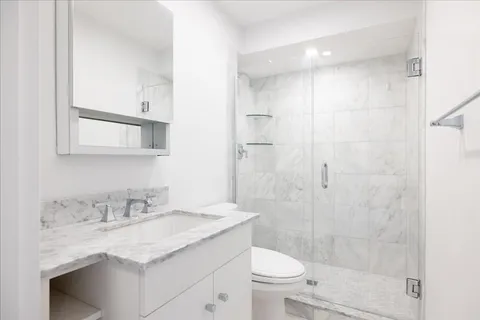 a bathroom with a granite countertop sink a toilet and shower