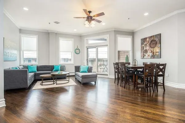 a living room with furniture wooden floor and a floor to ceiling window