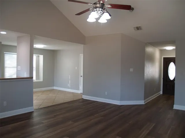a view of an empty room with wooden floor and a window