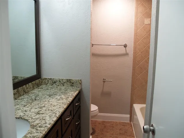 a bathroom with a granite countertop sink and toilet