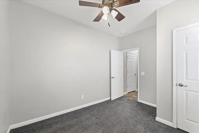 a view of an empty room and chandelier fan