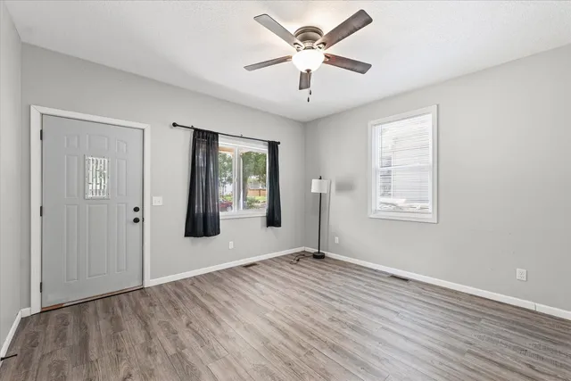 an empty room with wooden floor and windows