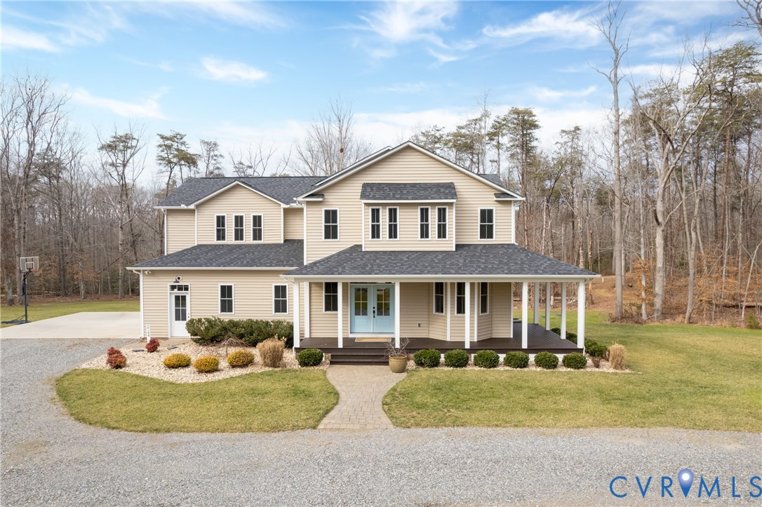Country-style home featuring covered porch, gravel