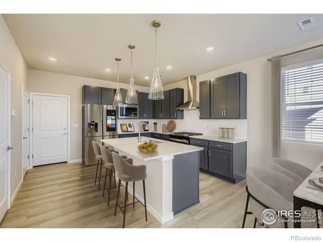 a kitchen with stainless steel appliances kitchen island granite countertop a sink and a refrigerator