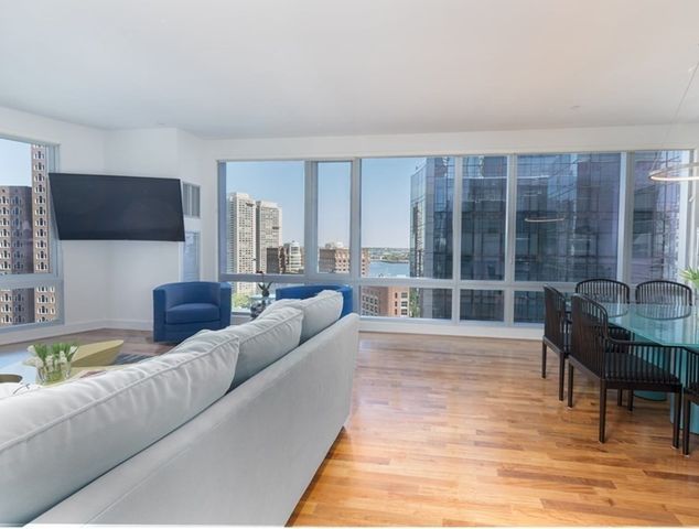 a living room with furniture a flat screen tv and a large window