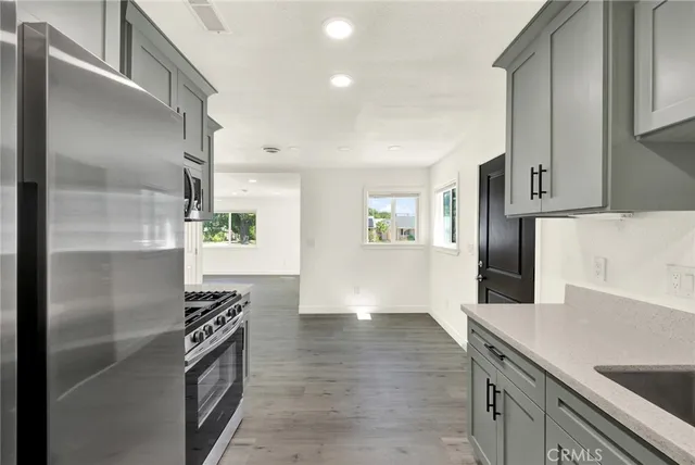 a kitchen with granite countertop a refrigerator and a stove top oven
